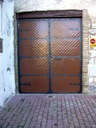 Puerta cochera con relieve en escama y bisagra medieval